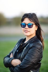 Portrait of young woman wearing sunglasses standing on field