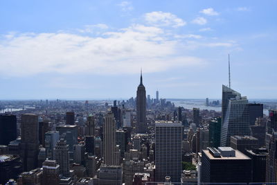 Aerial view of buildings in city against cloudy sky