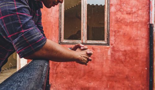 Side view midsection of man with hands clasped outside house