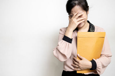 Mid section of person holding covering face against white background