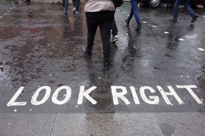 Low section of man with text on wet road