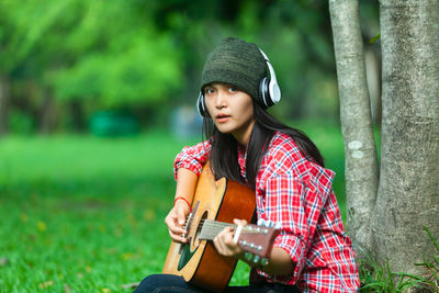 Portrait of woman playing guitar on field