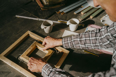 High angle view of senior craftsman making wooden frame at workshop