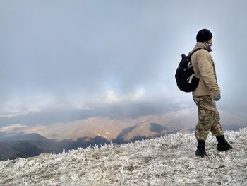 Full length of man standing on mountain against sky during winter