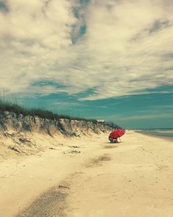 Scenic view of beach against cloudy sky