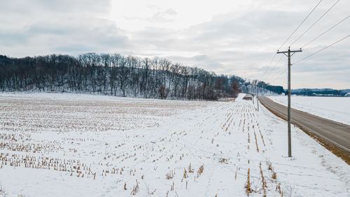 Rural scene of snow covered fields and hills along side the road.