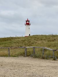 Lighthouse on field against sky