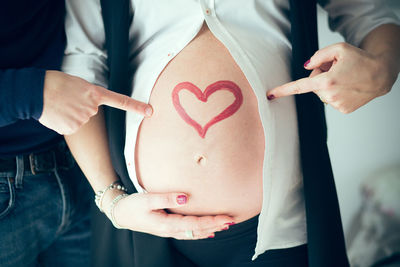 Close-up of couple pointing at pregnant belly