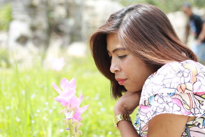 Side view of woman looking at purple flowers blooming outdoors