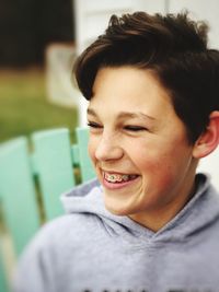 Close-up of smiling boy looking away at backyard