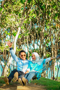 Full length of couple sitting on hammock