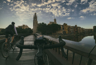 Man riding bicycle on railing in city against sky