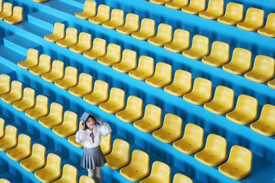 High angle portrait of young woman with book standing in stadium