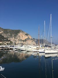 Sailboats moored at harbor against clear blue sky