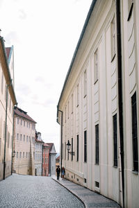 Rear view of man walking on street amidst buildings in city