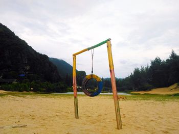 Bicycle on swing in playground against sky