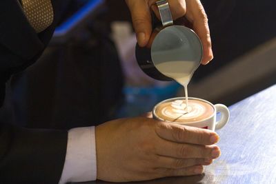 Midsection of barista making coffee in cafe