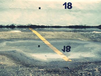 Reflection of number 18 on wall at puddle