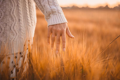 Midsection of woman on field during sunset