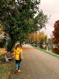 Rear view full length of woman walking on road during autumn