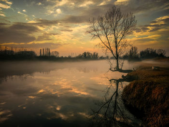 Scenic view of lake against dramatic sky during sunset