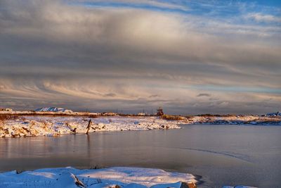 Scenic view of snow covered landscape against sky at sunset