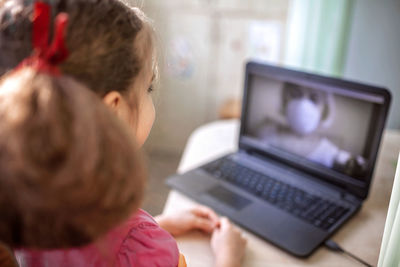 Rear view of woman using mobile phone at home