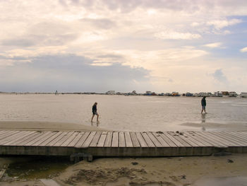 Men walking on shore against sky