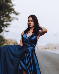 Young woman in blue dress standing on road