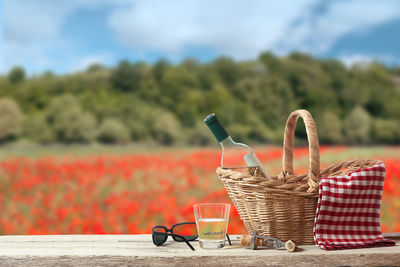 Red chili peppers in basket on table against sky