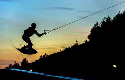Low angle view of silhouette woman jumping at sunset