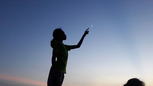 Rear view of silhouette girl standing against clear sky