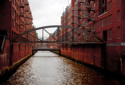 Bridge over river in city against sky