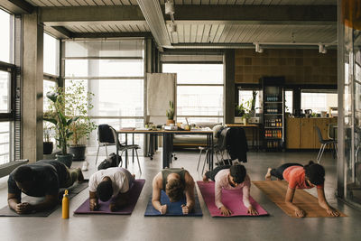 Multiracial colleagues practicing plank position on exercise mats in office