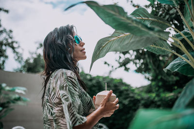 Side view of a young woman holding plant