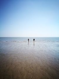 People at beach against clear sky