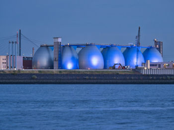 Illuminated gas tanks by waste water treatment plant on river elbe at night