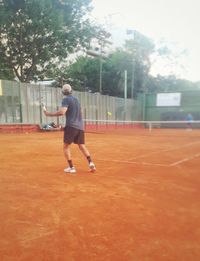 Full length of man playing with ball in background