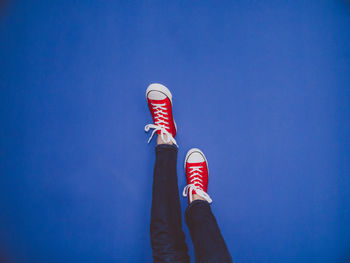 Low section of person standing against blue sky