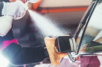 Midsection of man washing car in garage