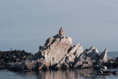 Scenic view of unique rock formation in sea against sky