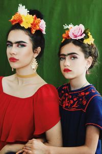 Portrait of women wearing flowers on hair against curtain