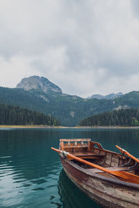 Boat moored on lake against sky