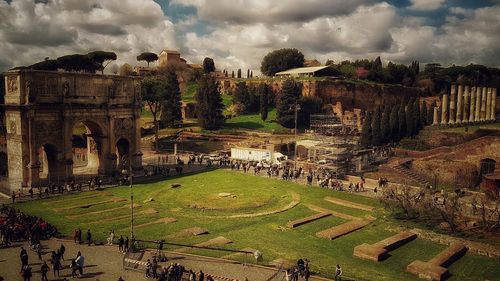 Panoramic view of tourists on landscape against cloudy sky