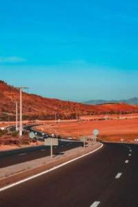 Road by landscape against blue sky