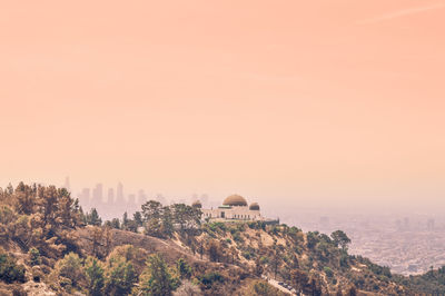 Trees and buildings against sky during sunset