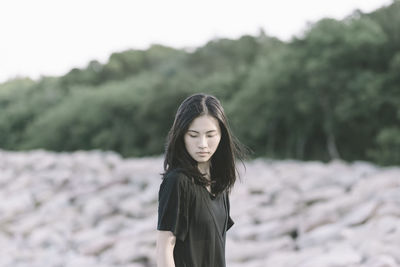 Young woman standing against trees