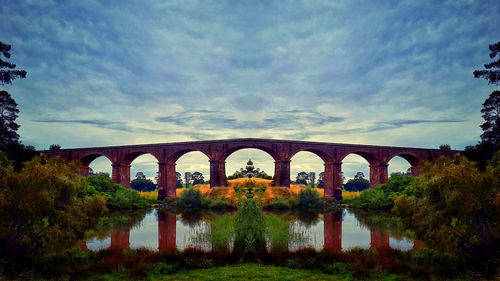 Arch bridge over river against sky