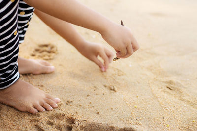 Low section of girl playing with sand at beach