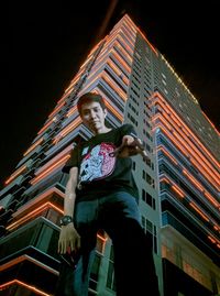 Low angle view of woman standing on illuminated building against sky at night
